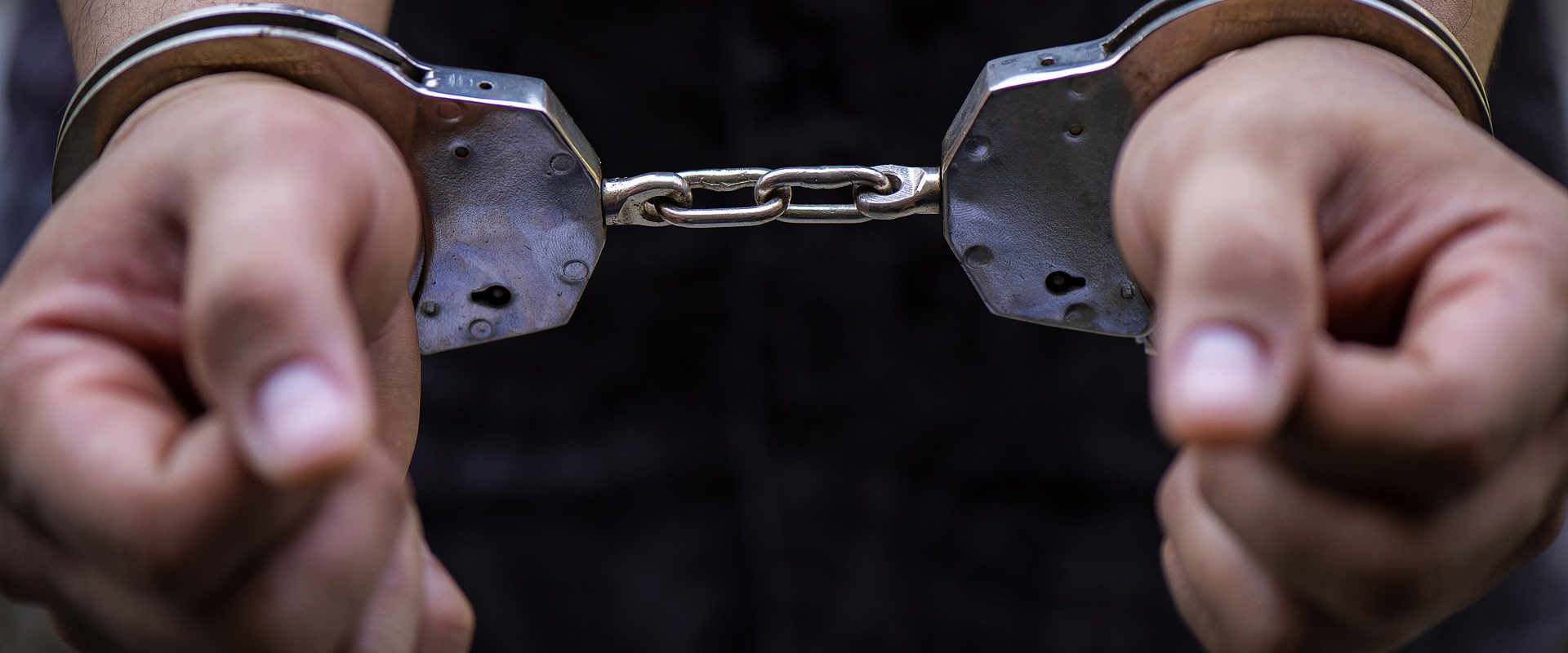 Man’s hand is locked with the handcuffs Man's hand is locked with the handcuffs